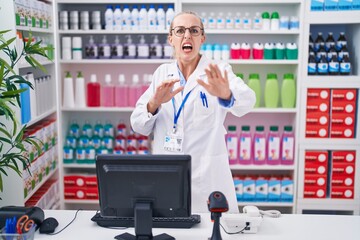 Poster - Young caucasian woman working at pharmacy drugstore afraid and terrified with fear expression stop gesture with hands, shouting in shock. panic concept.