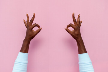 african american male hands show ok sign on pink isolated background