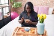 © Krakenimages.com - African american woman having gift breakfast sitting on bed at bedroom
