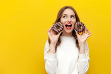 Young Cute Girl Holding Two Chocolate Donuts Over Yellow Isolated Background, Woman Screaming With Open Mouth