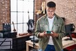 © Krakenimages.com - Young hispanic man musician using smartphone at music studio