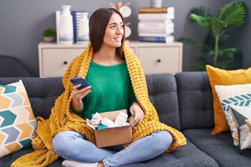 Sticker - Young beautiful hispanic woman using smartphone holding pills of delivery package at home