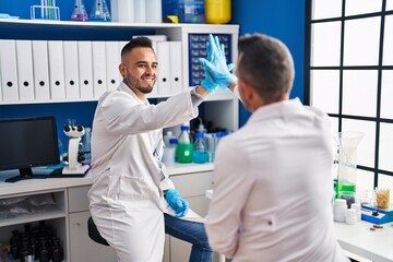 Sticker - Two men scientists smiling confident high five with hands raised up at laboratory