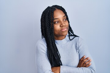 Wall Mural - African american woman standing over blue background looking to the side with arms crossed convinced and confident