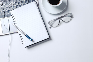 Modern style of working desk with computer screen, keyboard, earphone and blank notebook. Top view, flat lay