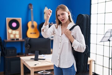 Canvas Print - Young caucasian woman holding guitar case annoyed and frustrated shouting with anger, yelling crazy with anger and hand raised