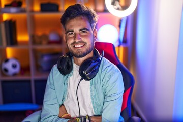 Sticker - Young hispanic man streamer smiling confident sitting with arms crossed gesture at gaming room