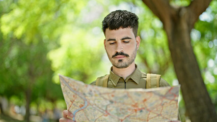 Sticker - Young hispanic man tourist wearing backpack looking map at park