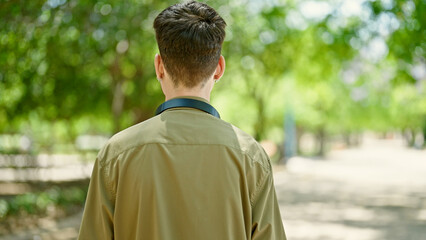 Sticker - Young hispanic man standing backwards wearing headphones at park