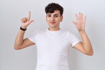 Canvas Print - Young non binary man wearing casual white t shirt showing and pointing up with fingers number seven while smiling confident and happy.