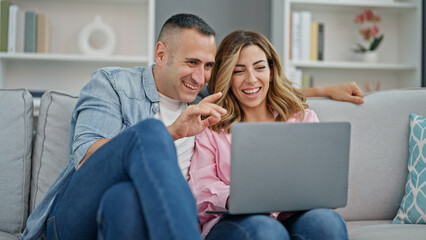 Canvas Print - Man and woman couple using laptop sitting on sofa at home