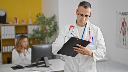 Canvas Print - Man and woman doctors writing medical report using computer working at the clinic