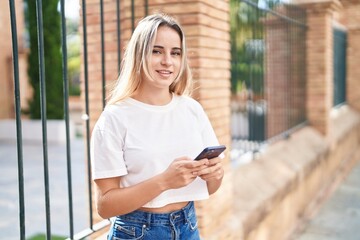 Poster - Young blonde woman smiling confident using smartphone at street