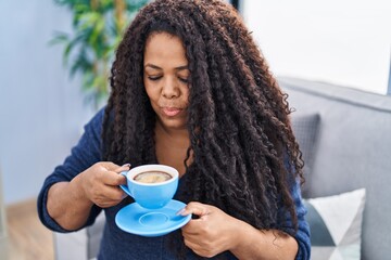 Canvas Print - African american woman drinking coffee sitting on sofa at home