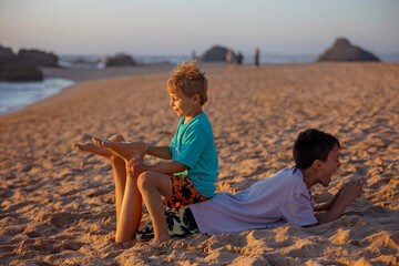 Sticker - Child, tickling sibling on the beach on the feet with feather, kid cover in sand, smiling, laughing