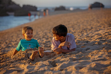 Sticker - Child, tickling sibling on the beach on the feet with feather, kid cover in sand, smiling, laughing