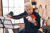 Fototapeta  - Senior man musician playing violin at music studio