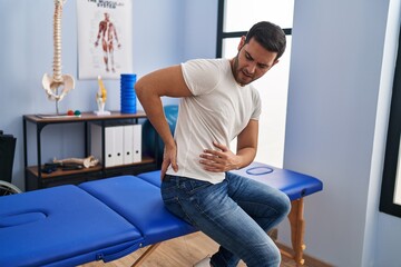 Wall Mural - Young hispanic man injured physiotherapy patient suffering for backache at rehab clinic