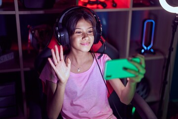 Poster - Young girl playing video games with smartphone looking positive and happy standing and smiling with a confident smile showing teeth