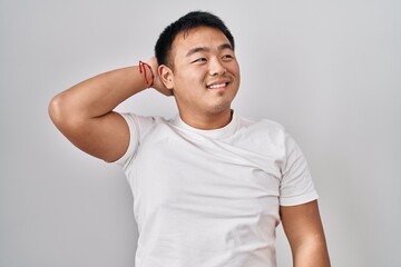 Poster - Young chinese man standing over white background smiling confident touching hair with hand up gesture, posing attractive and fashionable