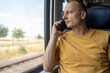 © Nenad - Mobile Call. Smiling Middle Aged Businessman Talking On Cellphone In Train While Traveling, Happy Man Having Pleasant Phone Conversation