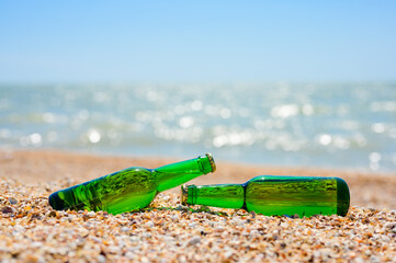 Two bottles of beer lie on the beach on a hot day. Seaside concept. Selective focus on bottle