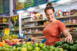 Consumer evaluates quality of avocado in supermarket.