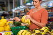 Consumer chooses bunch of banana in hortifruti.