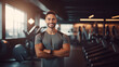 © Tetiana - Muscular brunette man in sportswear, smiling and looking at the camera on the background of the gym with copy space. Personal trainer. The concept of a healthy lifestyle and sports.
