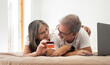 © Prostock-studio - Happy old caucasian wife hugging husband showing credit card, lies on bed with laptop, enjoy online shopping