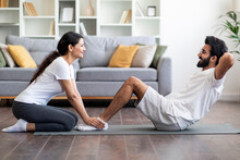 Happy Young Indian Couple Exercising At Home Together, Doing Sit-ups