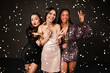 © Prostock-studio - Cheerful multicultural ladies in nice outfits posing among falling confetti