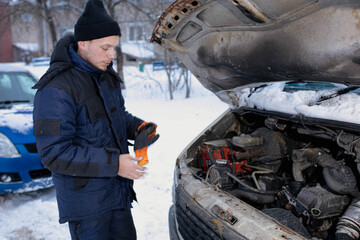 Wall Mural - man in winter clothes fixing a truck in winter with an open hood