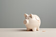 Broken piggy bank on white table and gray wall background.