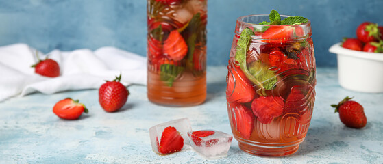 Glass of fresh strawberry lemonade on blue background