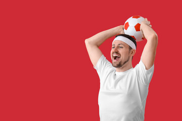 Wall Mural - Happy soccer player with ball on red background