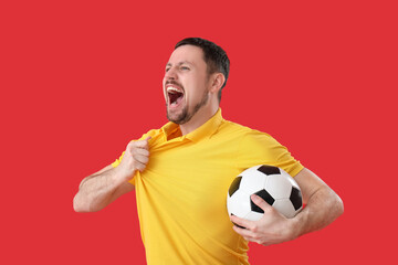 Wall Mural - Emotional man with soccer ball on red background