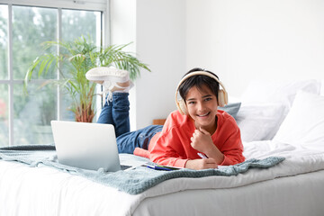 Wall Mural - Little boy with headphones studying in bedroom