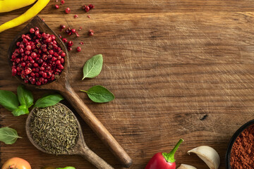 Poster - Wooden spoons with red pepper and dry thyme on wood table with copy space. Food cooking ingredients background top view
