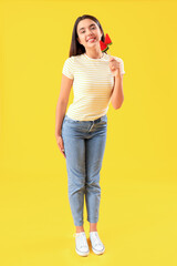 Sticker - Beautiful happy young woman with watermelon lollipops on yellow background