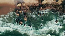 Top View Of A Sandy Beach And A Stone Reef On The Seashore, Waves Wash Over Large Rocks, Drone Video