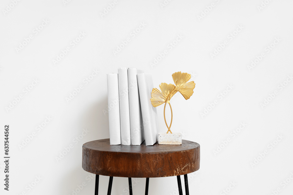 Stack of books with decor on table near light wall