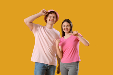 Wall Mural - Young couple in t-shirts on yellow background