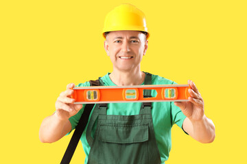 Poster - Mature worker with level on yellow background. Labor Day celebration