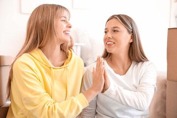 Wall Mural - Female students giving each other high-five in dorm room on moving day