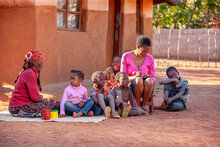 Village African Family Sited In The Yard In Front Of The House, Three Generations Grandmother, Mother, Kids.