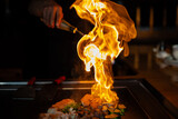Fototapeta Kwiaty - Chef cooking in Japanese teppanyaki restaurant