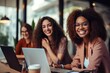 © The Little Hut - Generative AI : Happy multiethnic women have fun seated at desk in workplace. Female teammates, distracted from work, tell jokes, laughing, having goods friendly work relations, engaged in teamwork an