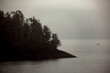 Grey, misty, foggy morning in archipelago near Sitka, Alaska with small islands channel cruising and houses