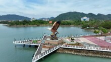 Aerial Panning Shot Of Tourists By Eagle Statue At Dataran Lang On Sea Near Mountains - Langkawi, Malaysia